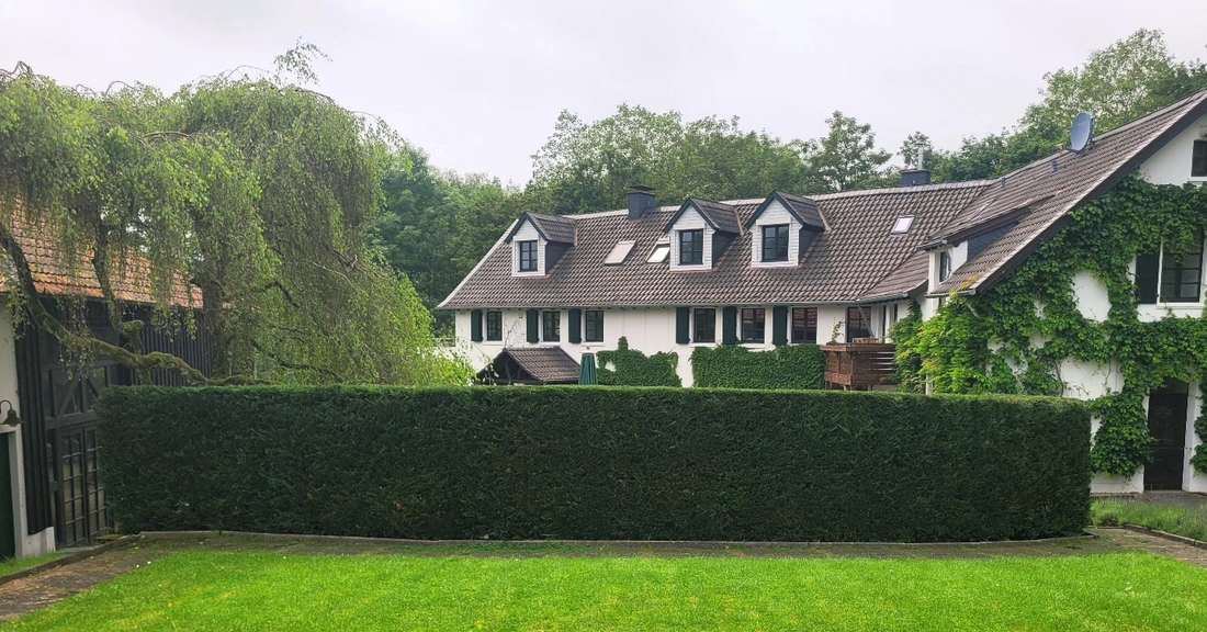 Langes Landhaus mit durchlaufender geschnittener Hecke